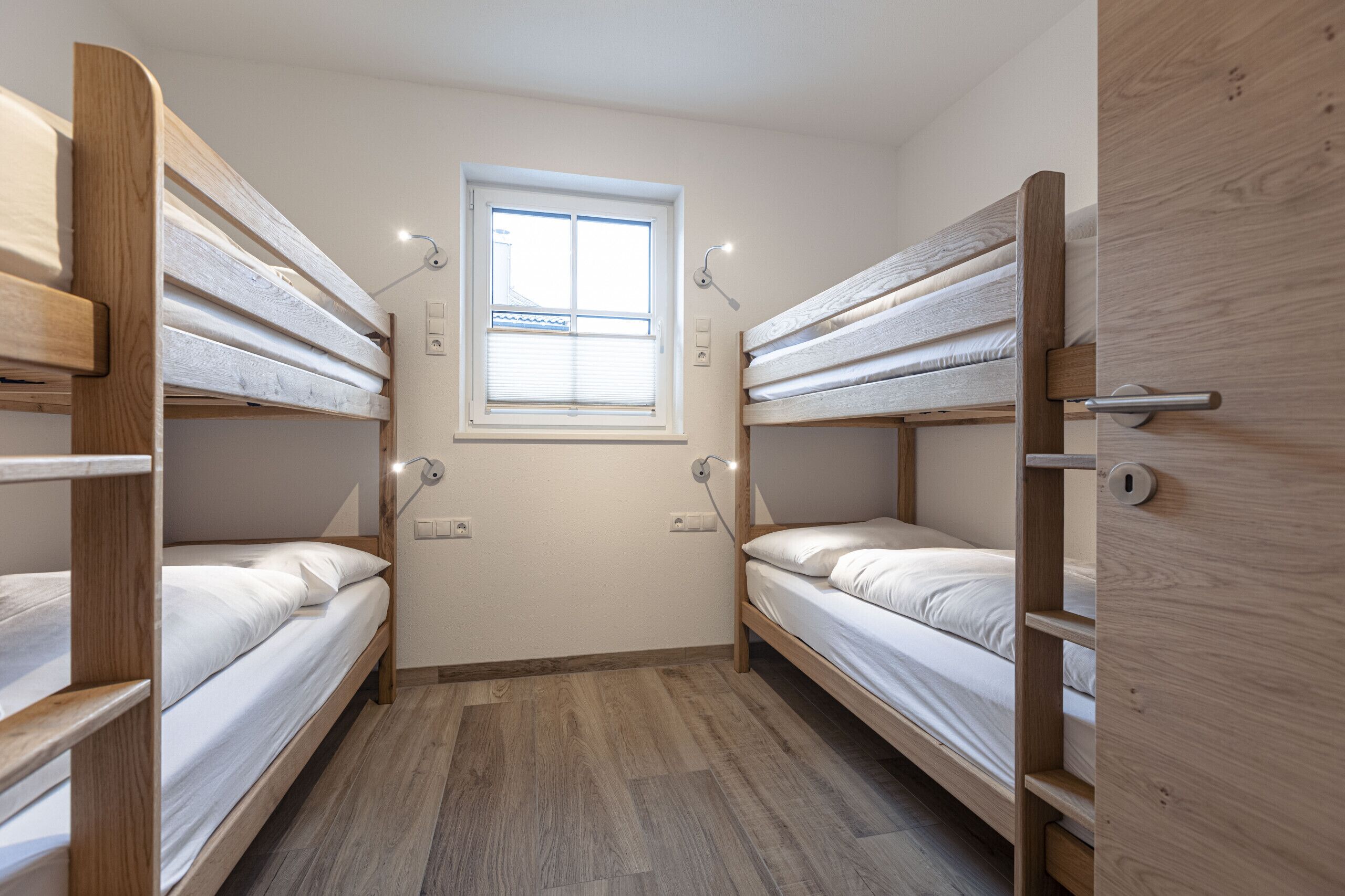 A compact room with bunk beds, a window, and a door.