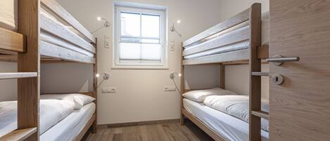A compact room with bunk beds, a window, and a door.