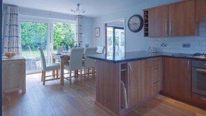 Eine moderne Küche mit Holzausstattung, einer Marmorarbeitsplatte und einem Essbereich mit Tisch und Stühlen.