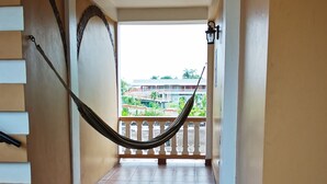 A corridor with tiled flooring, a hammock, and a view of greenery outside. - Hotel de la Fuente (Orange Walk)