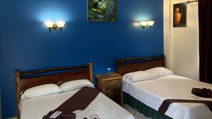 A hotel room with two beds, a painting on the wall, and a water bottle on the nightstand. - Hotel de la Fuente (Orange Walk)