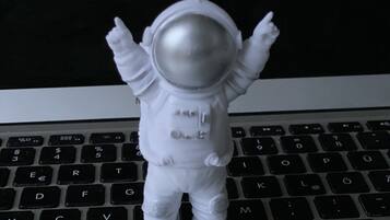 A white astronaut figurine standing on a laptop keyboard.