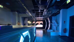 A futuristic lobby with a central reception desk, a digital display, and a statue. - Space Night - Hostel (Berlin)