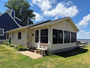 Ein eingeschossiges Haus mit Veranda, überdachter Terrasse und Blick auf das Wasser.