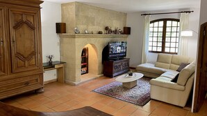 A living room with a fireplace, a television, a sofa, and a cabinet.
