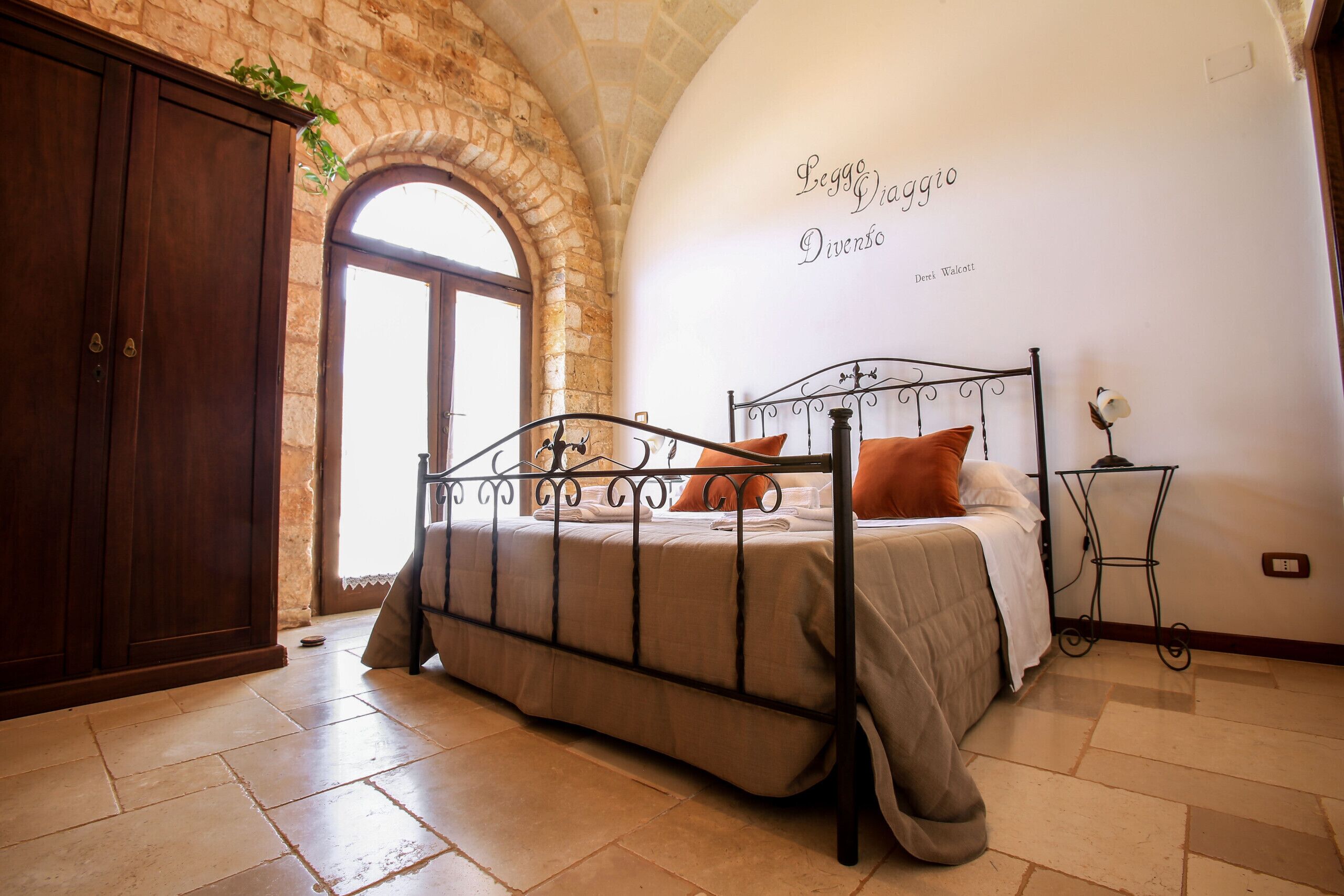 A bedroom with a stone archway, a bed with a metal frame, and a wall with text.