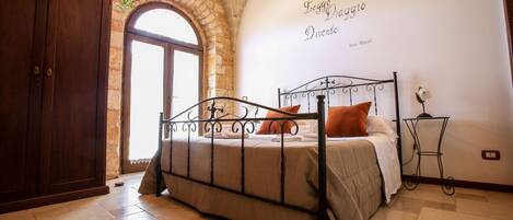 A bedroom with a stone archway, a bed with a metal frame, and a wall with text.