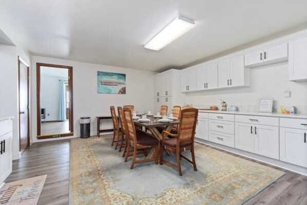 A dining area with a table set for four, surrounded by wooden chairs, white cabinets, and a patterned rug. - Oceanfront Vacation House - Pet Friendly (Rockaway Beach)