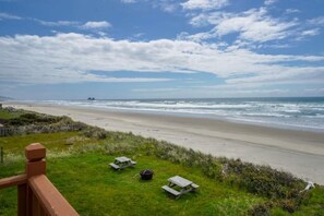 A beach with picnic tables and a wooden fence. - Oceanfront Vacation House - Pet Friendly (Rockaway Beach)