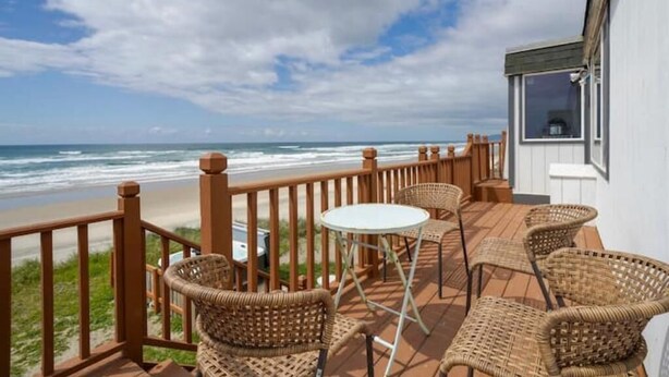 Un balcon doté de meubles en osier et offrant une vue sur la plage.