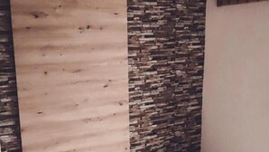 A room with a wooden sliding door and a stone accent wall. - Ferienwohnung auf dem Lande (Twedt)