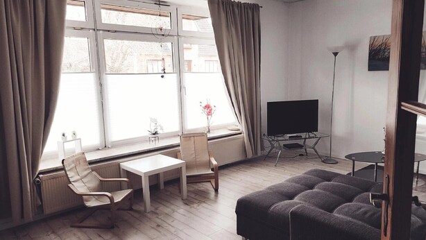A living room with a sofa, two chairs, a small table, a TV on a stand, and a radiator. - Ferienwohnung auf dem Lande (Twedt)