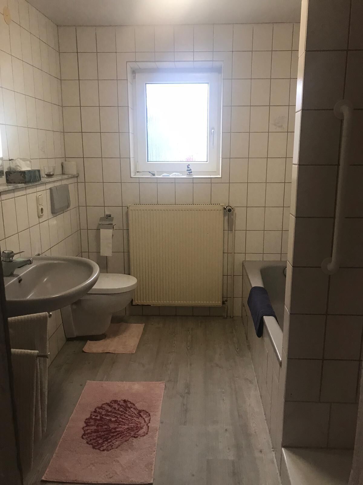 Un bagno piccolo rivestito di piastrelle, con il water, il lavandino e una finestra.