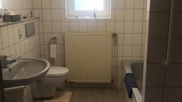 Un bagno piccolo rivestito di piastrelle, con il water, il lavandino e una finestra.