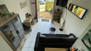 Un espacio habitable compacto con kitchenette, comedor y zona de estar con sofá y una mesita.