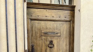 A wooden door with a metal handle and a nameplate, set in a textured wall. - Maison de Village Atypique (Vidauban)