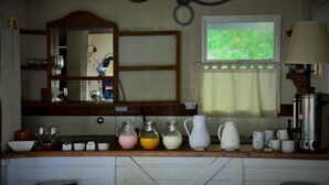 A kitchen with a wooden countertop, a mirror, a window with a view of greenery, and various kitchen items.