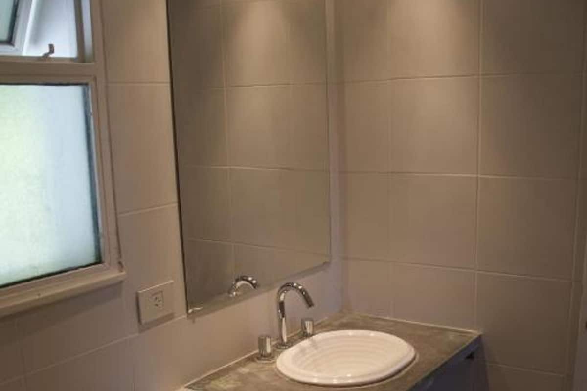 Un baño con inodoro, lavamanos y espejo.