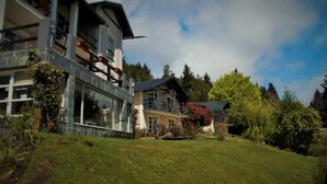 A modern building with a glass facade, a large balcony, and a traditional house with a sloped roof. - Impeccable 2BR Condo w Spacious Balcony and Waterfront (San Carlos de Bariloche)