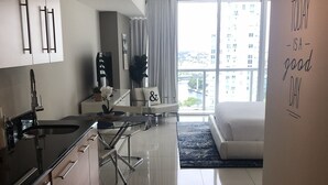 A modern kitchen with a dining area, a large window with a view of buildings, and a motivational quote on the wall. - Studio River & City View (Miami)