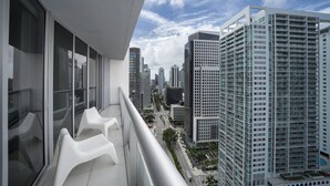 A high-rise building with a balcony featuring white plastic chairs. - Studio River & City View (Miami)