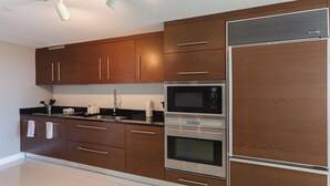 A modern kitchen with wooden cabinets, stainless steel appliances, and a tiled floor. - Studio River & City View (Miami)
