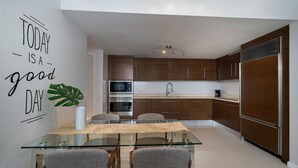 Eine moderne Küche mit Holzschränken, Edelstahlgeräten und einem Glastisch.