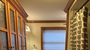 Ein Badezimmer mit Holzkabinent, Waschbecken, Fenster und Duschvorhang.