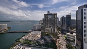 A high-rise building with a modern architectural design, situated near a body of water with a marina. - Presidential Ocean View (Miami)