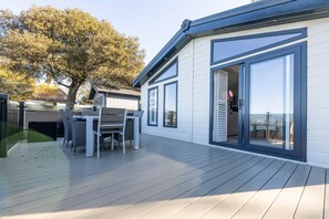 Ein modernes Haus mit einer Terrasse, einem Essbereich und einem großen Fenster.