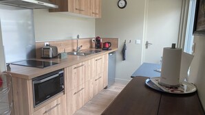 Een moderne keuken met houten kasten, roestvrijstalen apparatuur en een ingebouwde magnetron.