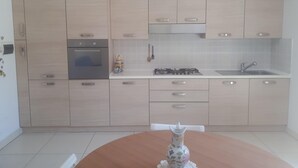 Una cocina moderna con armarios de madera clara, horno empotrado, estufa a gas y pileta.