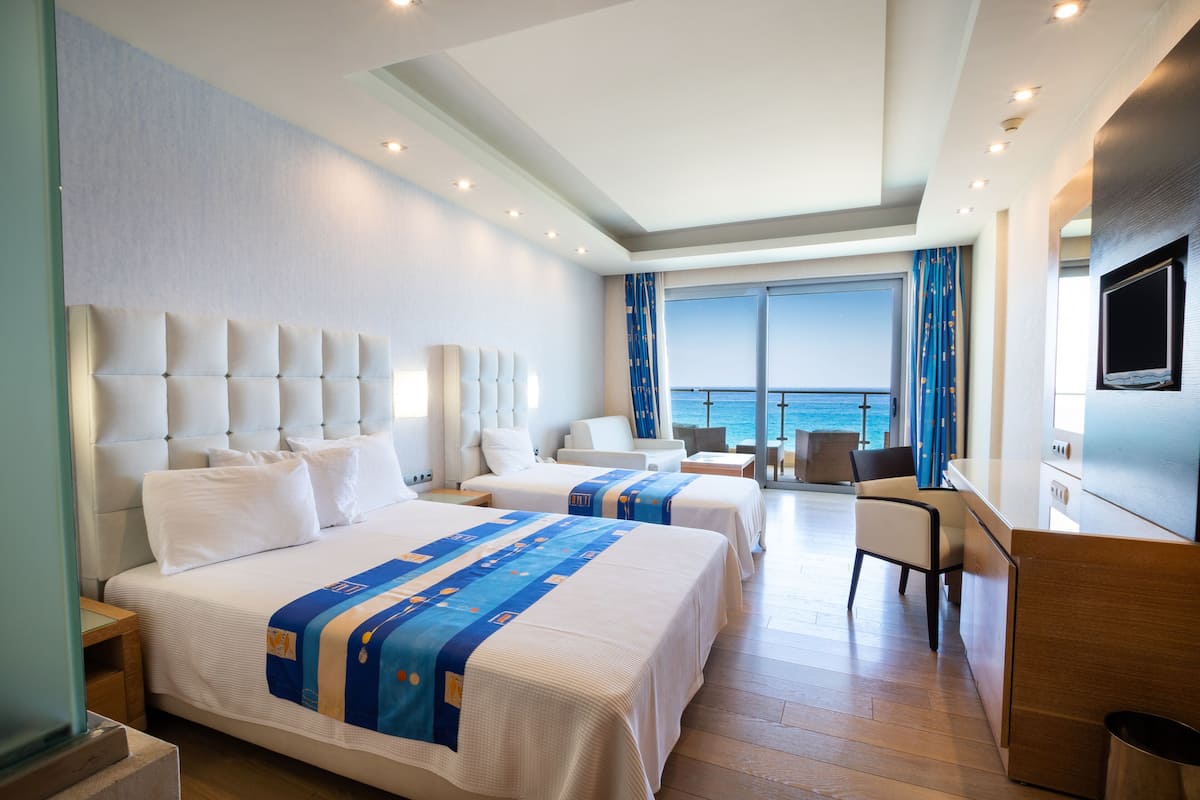 A hotel room with two beds, a desk, a chair, and a TV.