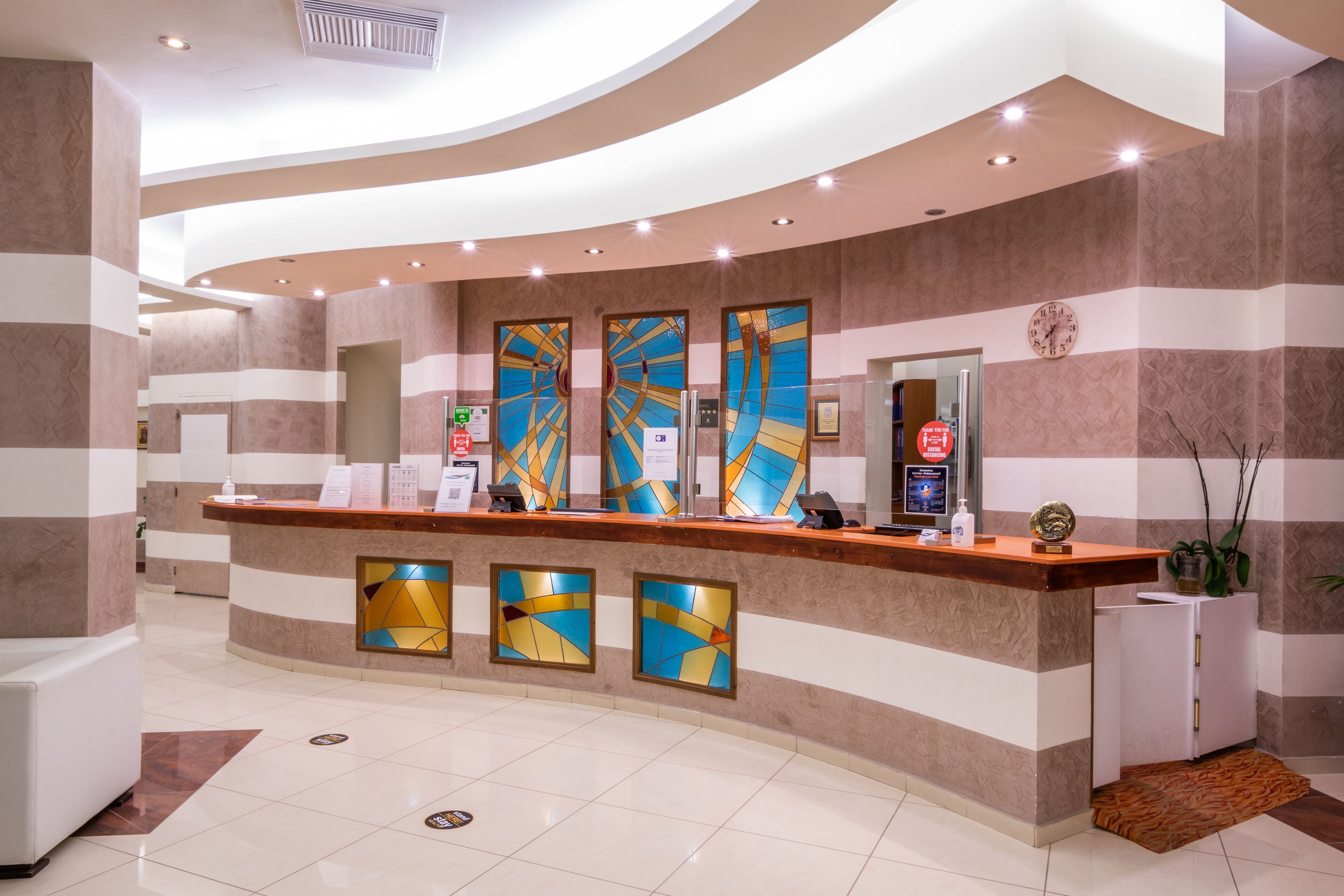 A reception area with a curved counter, a clock, and a potted plant.