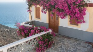 A coastal building with pink bougainvillea, stone flooring, and a view of the sea. - Konstantinos Palace (Karpathos)