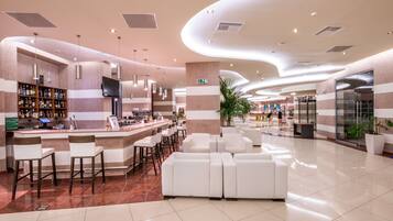 A modern lobby with a bar area, seating, and a large plant.