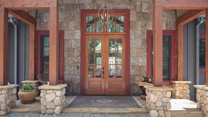 A wooden entrance with a stone facade, a double door, and a chandelier. - Welcome to A Little Bit O' Heaven! (Lake Toxaway)