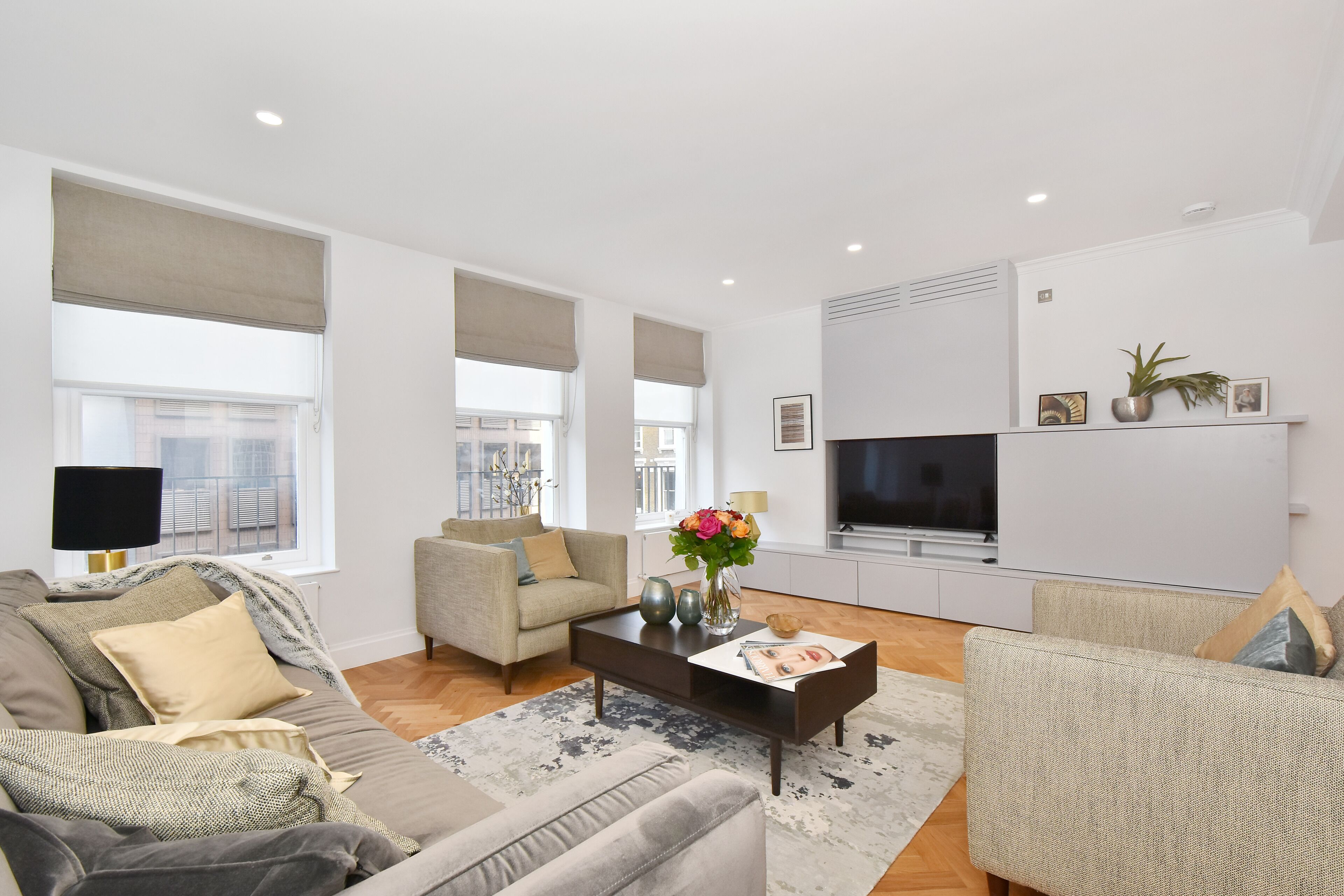 A modern living room with a sofa, armchairs, a coffee table, and a TV.