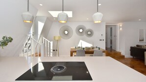Uma cozinha moderna com ilha central, iluminação pendente e área de jantar com mesa e cadeiras.