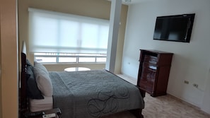 A hotel room with a bed, a dresser, a TV mounted on the wall, and a balcony with a view. - Hotel Royal Durán (Duran)