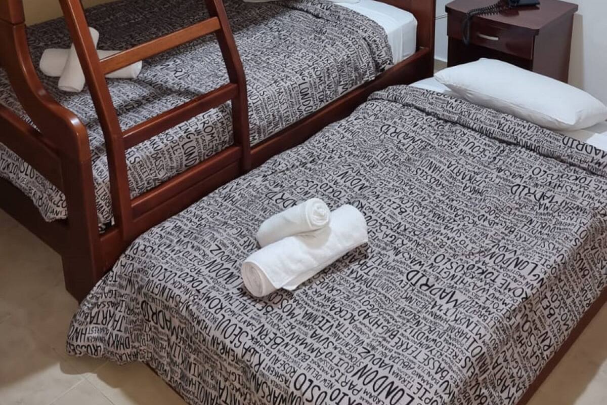 Ein Etagenbett mit gemusterten Betttextilien, ein Nachttisch mit Telefon und ein Bild an der Wand.