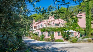 A pink villa with a gravel driveway, surrounded by lush greenery and trees. - Independent apartment of two bedrooms of high standing and comfort. (Salernes)