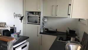 A compact kitchen with a built-in oven, a toaster, a sink, and a dishwasher.