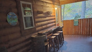 A wooden cabin with a deck, a table, and a chair.