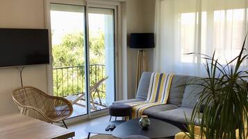 Un salon comprenant un canapé, des fauteuils, une table basse, un téléviseur et un balcon avec vue.