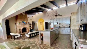 A spacious kitchen with a central island, a brick fireplace, and white cabinetry.