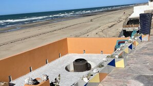 A rooftop terrace with a view of the beach and ocean.
