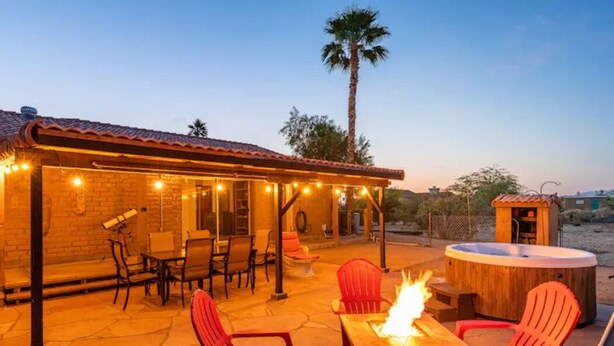 An outdoor patio with a fire feature, seating, and a hot tub.