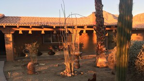 A desert-style house with a tiled roof, a cactus, and a dog in the yard.