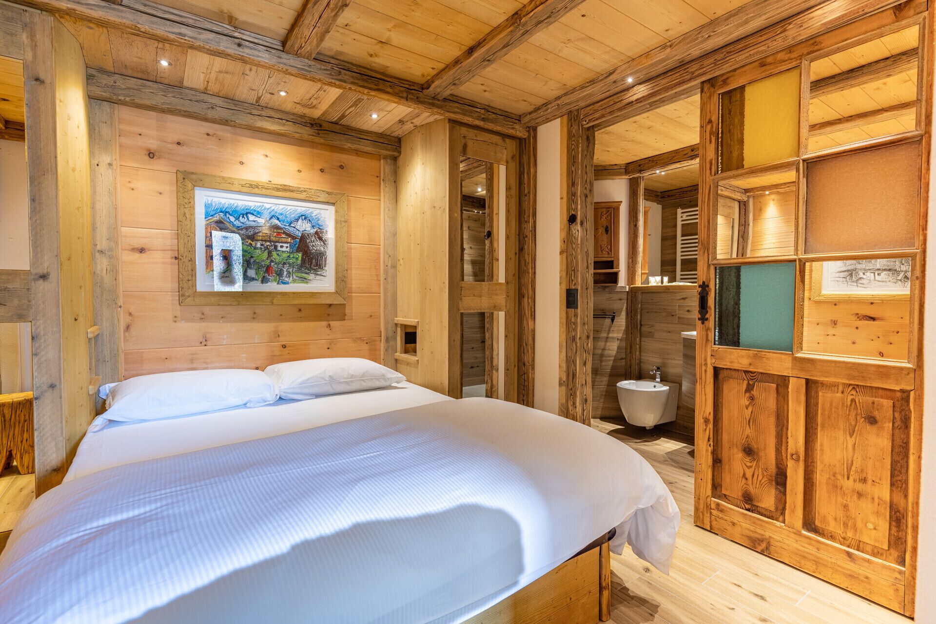 Una habitación de madera con una cama, paredes de madera y un cuadro.
